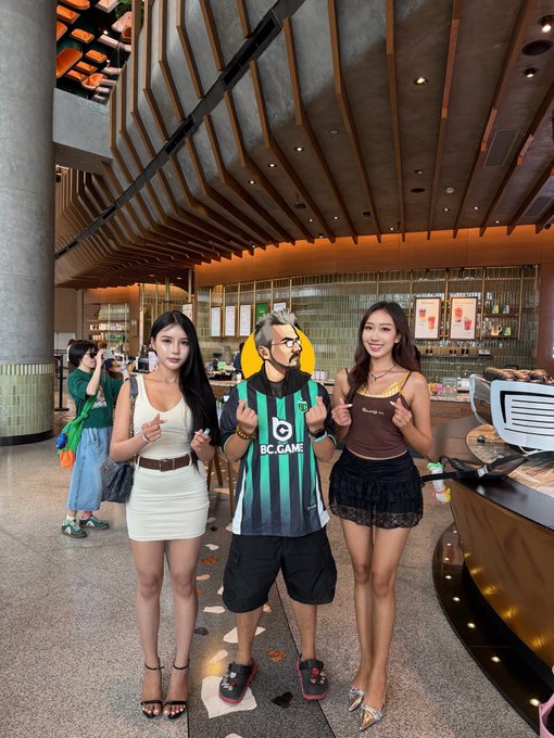 The image shows three people standing together, with one of them wearing a green shirt that says "bcgame" on it. The other two individuals are posing for a photo while standing near a bar or restaurant setting. A sign can be seen behind them, which reads "话不多说福利时间抽 主题球衣".