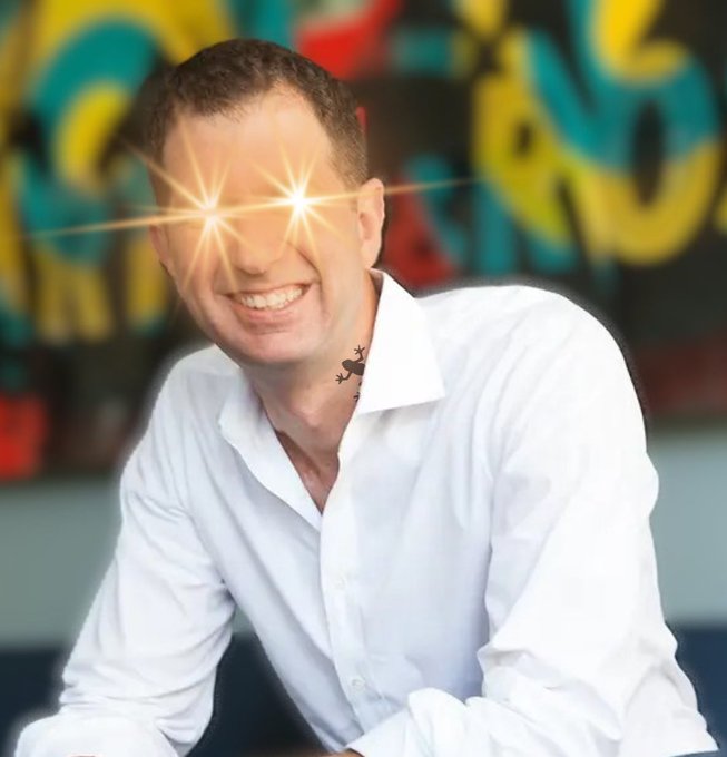 The image features a man wearing a white shirt with yellow eyeshadow applied to his eyes, giving him an interesting and unique appearance. The background of the photo shows a colorful graffiti wall, which adds to the overall visual appeal of the scene. The caption provided in the image seems to be related to a post on social media or a conversation about a specific topic. However, without more context, it is difficult to determine the exact nature of the post or its relevance to the man's appearance and the colorful graffiti wall.