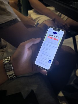 A person holds a smartphone displaying a profile for 'SUMMIT TAYLOR' in a dark setting.