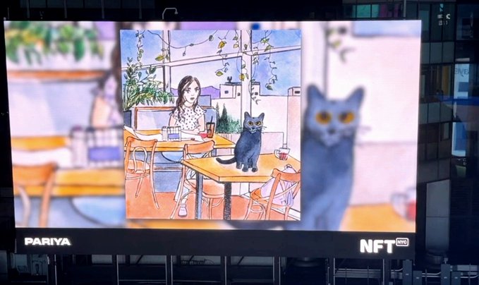 A billboard advertisement by PARIYA labeled 'NFT PRO' displaying an anime-style illustration of a girl at a café table with a gray cat, alongside a 3D rendering of the cat on the right side.