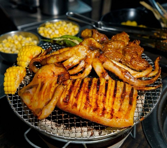 A delicious spread of grilled squid, marinated chicken, corn on the cob, and corn kernels cooks over a tabletop grill, evoking the casual, social atmosphere of a Korean BBQ dinner. The image complements the post's "what's for dinner" theme, providing a mouthwatering visual while the author shifts focus to researching @CNPYNetwork.