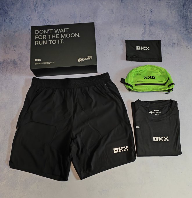 A flat-lay product photo of OKX-branded merchandise including black shorts, a black t-shirt, a green waist bag, a black face covering, and a black box reading 'DON'T WAIT FOR THE MOON. RUN TO IT. THE NEW MONEY AND OKX'.