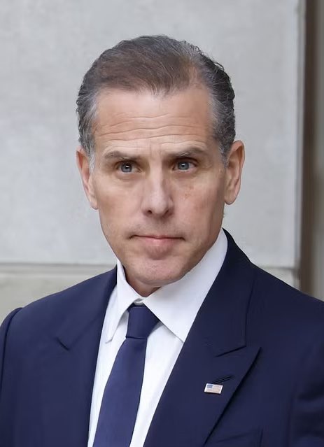 Hunter Biden, wearing a dark suit and blue tie with an American flag pin, appears in a close-up portrait outside a stone building. The image accompanies breaking news of his bold Bitcoin price prediction, suggesting he expects the cryptocurrency to reach $1 million within years rather than decades.