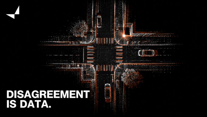 An aerial nighttime view of a four-way intersection with cars, overlaid with the text 'DISAGREEMENT IS DATA.'