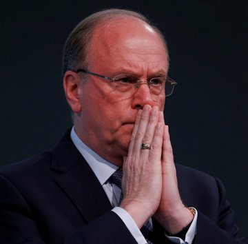 A bald man in glasses and a dark suit holds his hands together in a thoughtful, prayer-like pose, likely Larry Fink, the CEO of BlackRock, whose company is reported to have just deposited 1,948.07 BTC (worth $122.03 million) into Coinbase Prime.