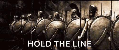 A cinematic, sepia-toned image of Spartan warriors holding shields and spears in formation, with the text 'HOLD THE LINE' overlaid in white.