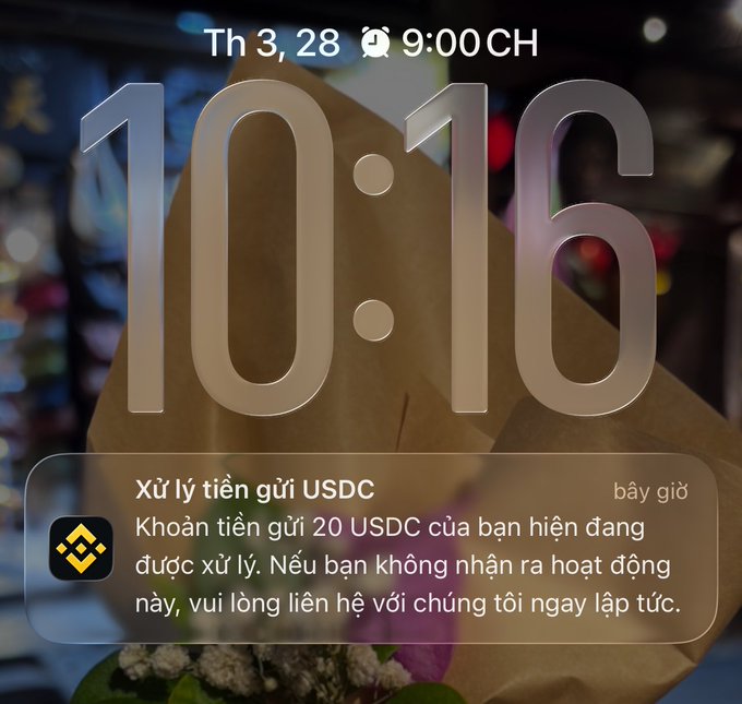 An iPhone lock screen displaying the time 10:16 and a Binance notification in Vietnamese about a 20 USDC deposit being processed.