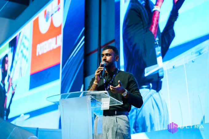 A man speaking into a microphone at a clear podium during a 'FutureLab' conference, with an 'ULTRA' logo visible in the bottom right corner.