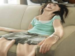 A woman with messy hair slumps lifelessly on a couch with her mouth agape and limbs sprawled, wearing a green top and skirt. The image humorously captures the exhausted, defeated energy of someone who has just suffered a sudden financial loss or "rug pull."