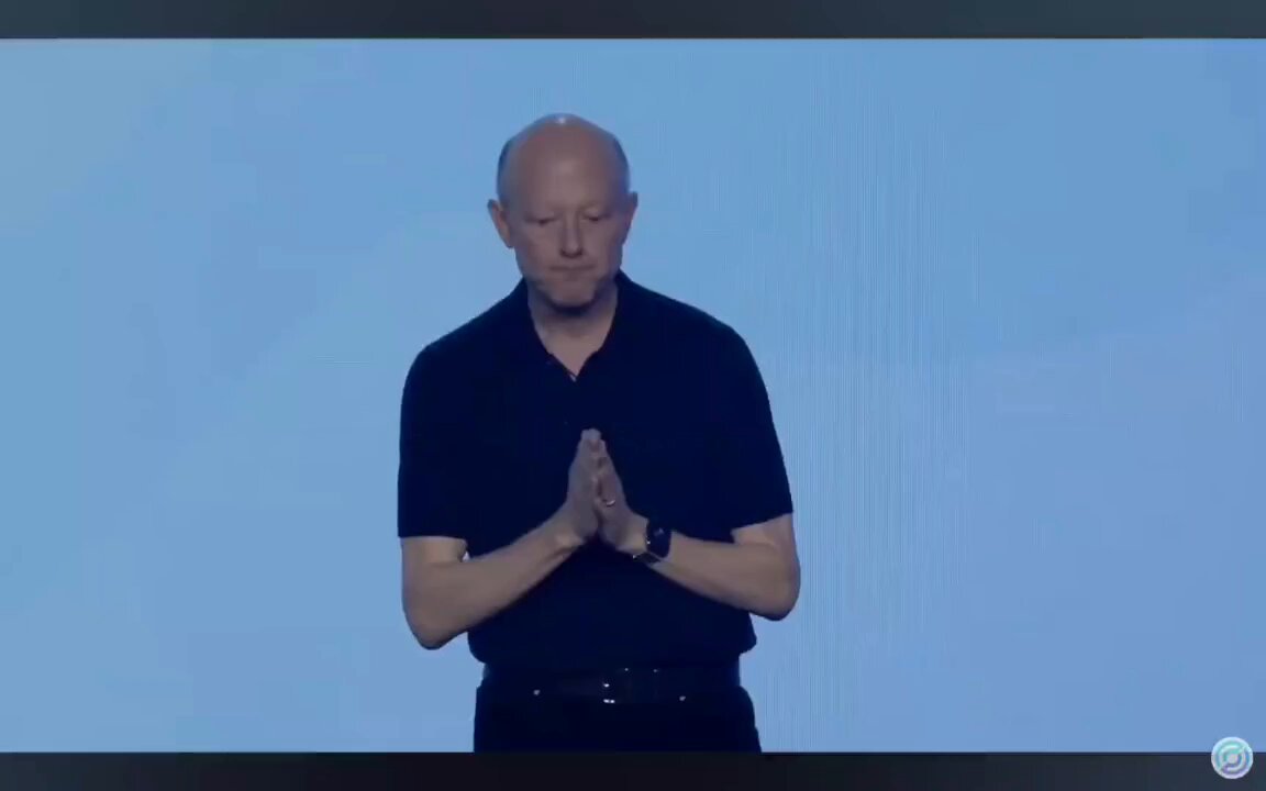 The image shows a man wearing a black shirt, standing against a blue background with his hands clasped together in front of him. The caption reads "Focus on what is in the image and how it relates to the post". This suggests that the main focus should be on the man's pose or expression rather than the surrounding elements like other objects or text present in the image.
