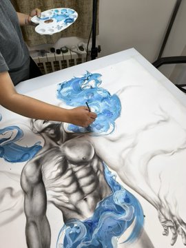 An artist is seen painting a large canvas featuring a muscular grayscale figure enveloped in blue smoke-like patterns, holding a palette of blue and white paints.
