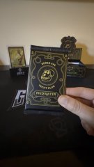 A hand holds a black-and-gold trading card labeled “POP MONSTER” in front of other similar cards.