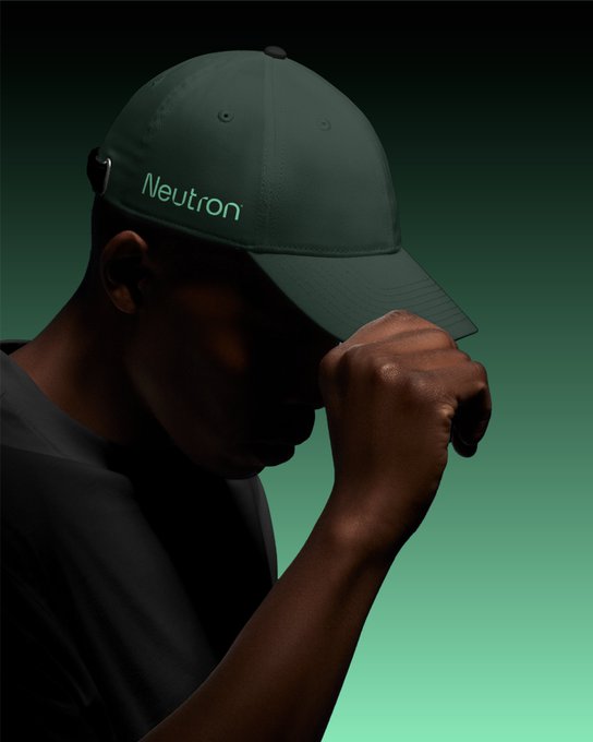 A man in a dark green 'Neutron' branded cap adjusts his brim against a green gradient background.