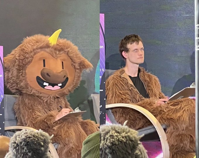 A split image shows Vitalik Buterin, the founder of Ethereum, seated beside someone in a furry mascot costume, both wearing matching brown furry outfits at what appears to be a public event. The image is presented humorously to highlight the unexpected or playful side of the typically serious crypto figure, paired with the caption "This is the founder of Ethereum btw" to draw attention to his presence.