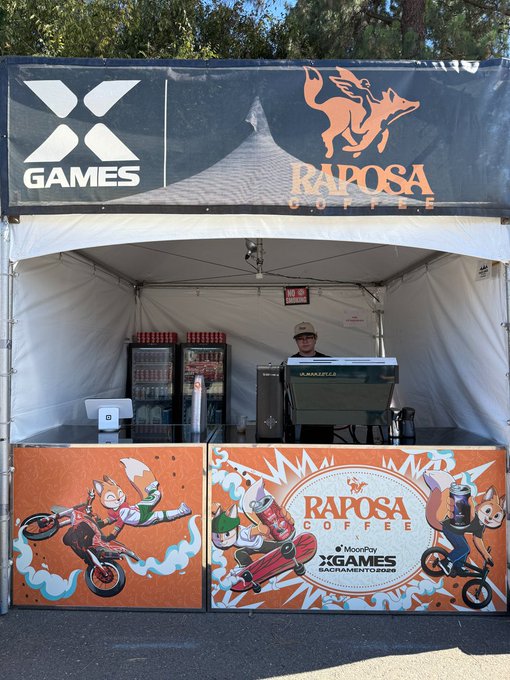 A Raposa Coffee booth at the X Games, featuring branded displays, an espresso machine, and cartoon fox illustrations, with the post tagging @XGames and @moonpay to promote their collaboration at the event.