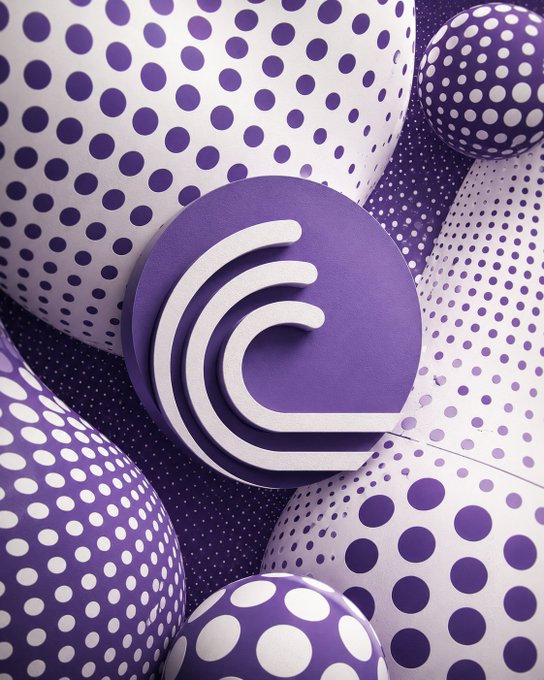 A 3D rendered graphic features a circular purple logo with a white swirling wave-like design, surrounded by purple and white spheres covered in polka dots of varying sizes.