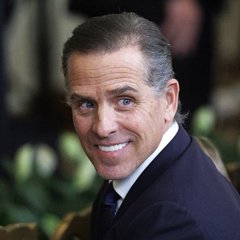 Hunter Biden smiles in a formal portrait wearing a dark suit and white shirt.
