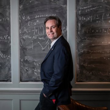 The accompanying post appears to be unrelated to the image, which shows a man in a dark blazer and red socks smiling while standing in front of chalkboards covered in mathematical equations and formulas.