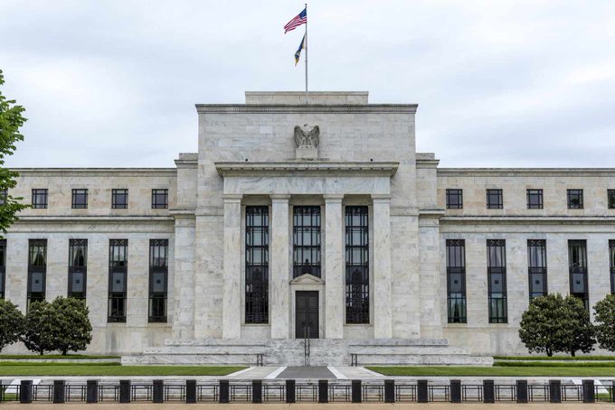 The Federal Reserve building stands prominently with an American flag atop its neoclassical marble façade, its iconic eagle emblem visible above the grand entrance columns. This stately institution, known for its economic research and surveys, conducted the report revealing that 10% of Americans now own cryptocurrency, highlighting crypto's growing mainstream adoption.