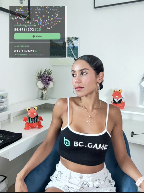A woman wearing a black 'BC.GAME' branded crop top sits in a chair with an overlay showing cryptocurrency earnings of 812.187621 BCD.
