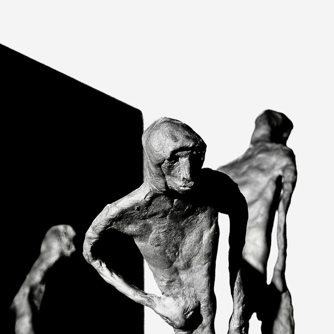 A black and white photo of several gaunt, elongated humanoid sculptures with hollow-looking features.