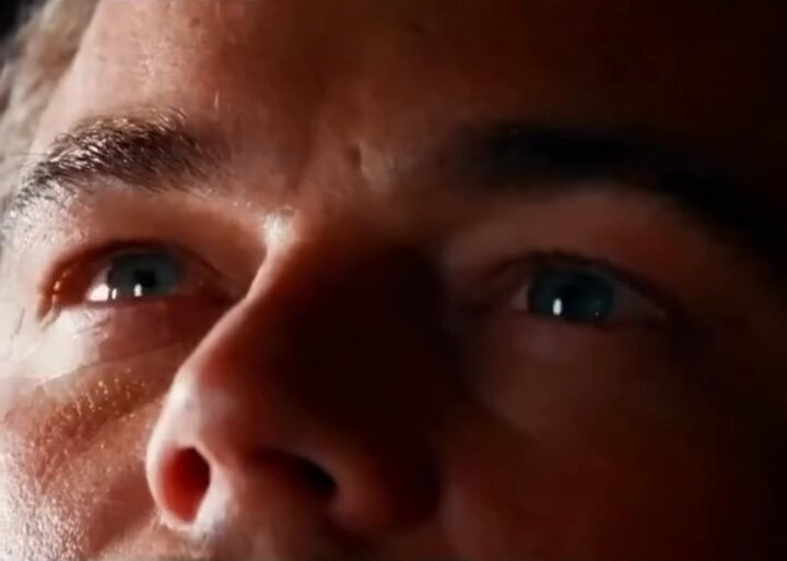 The image shows a close-up of a person's face, specifically focusing on their eyes. The person has blue eyes that are open wide as they gaze directly into the camera. The background appears to be dark or out of focus, drawing attention to the subject and making them the main focus of the photo.