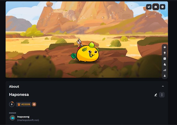 The image shows a cartoon character, possibly a frog or a fish, sitting on rocks with a smiley face. The text "About" is displayed at the top of the screen, while the post says "Just bought this beautiful Japanese axie @AxieInfinity @Ronin_Network". This suggests that someone has purchased and added an illustration to their social media account or blog, possibly related to the cartoon character in question.