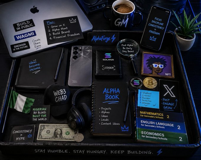 A flat-lay image of a productivity setup featuring a MacBook, phone, books, headphones, and various items labeled with motivational and crypto-related text such as 'BUILD IN PUBLIC', 'WAGMI', 'ALPHA BOOK', 'WEB3 CHAD', and 'STAY HUMBLE. STAY HUNGRY. KEEP BUILDING.'