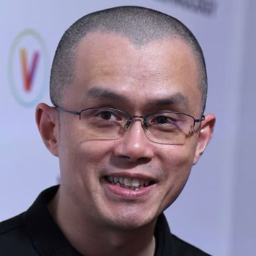 Changpeng Zhao (CZ), the Binance founder known for his signature shaved head and glasses, smiles at what appears to be a tech or financial event, shown here shortly after voicing his bold take on stablecoins and the future of digital economies.