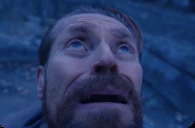 A close-up of a man with a beard looking upward with an expression of awe or shock, bathed in blue lighting.