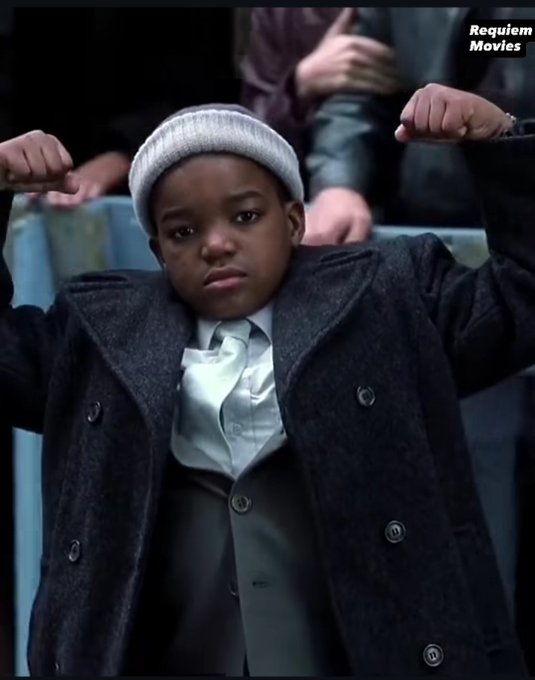 A young boy in a beanie and oversized coat flexes his arms with a serious expression, with a "Requiem Movies" watermark in the corner. The post appears unrelated to the image, using the child photo likely as an attention-grabbing visual to promote a MetaWin giveaway contest.