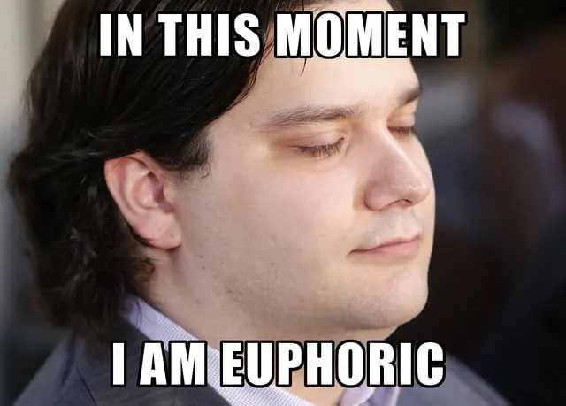 A close-up of a man with his eyes closed and a subtle smile, with meme text overlaid reading 'IN THIS MOMENT' at the top and 'I AM EUPHORIC' at the bottom.
