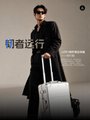 A man in a suit stands with a silver suitcase against a backdrop featuring Chinese characters and the English phrase "BEAUTIFUL JOURNEY."