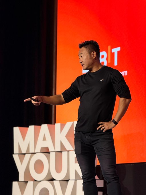 Ben, a representative from Bybit, delivers a keynote presentation on stage, gesturing toward the audience while wearing a black Bybit-branded shirt. The backdrop displays the Bybit logo alongside large "MAKE YOUR MOVE" lettering, reinforcing the post's message about the wrap-up of his speech and the event's call-to-action branding.