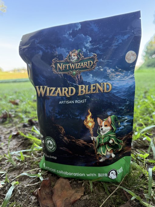 A bag of NFTWIZARD 'Wizard Blend' artisan roast coffee sitting on grass, featuring a corgi wizard illustration and noting it is an 'Official collaboration with BirbCafe'.