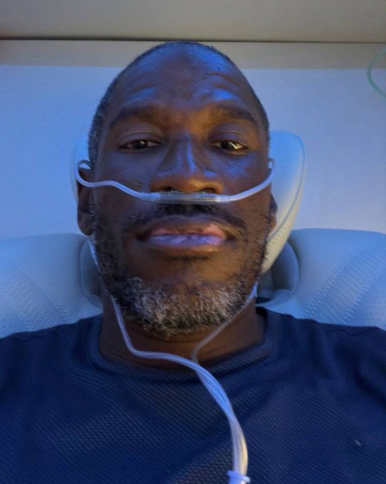 The image shows a man lying in a hospital bed receiving oxygen through a nasal cannula, visually representing the "life support" metaphor in the caption about sidelined Hyperliquid traders whose positions or capital have been exhausted awaiting a market move.