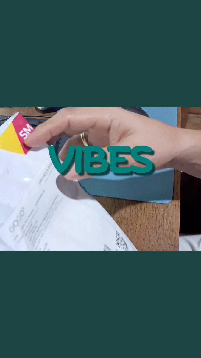 The image features a hand holding a green sticker with the word "VIBES" written on it, which appears to be a promotional sticker for an event or product. The background of the image is a light blue color that contrasts with the green sticker. There are also some text elements in the image, including the words "@YieldGuild Community Questing", "@LootStackPH", and "VIBES". These texts seem to be related to the sticker's promotion or context surrounding it.
