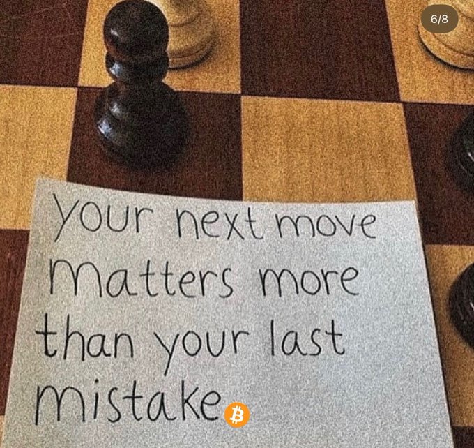 A handwritten note on a paper resting on a chessboard reads "Your next move Matters more than your last mistake," featuring a small Bitcoin logo, with a black chess pawn visible in the background.