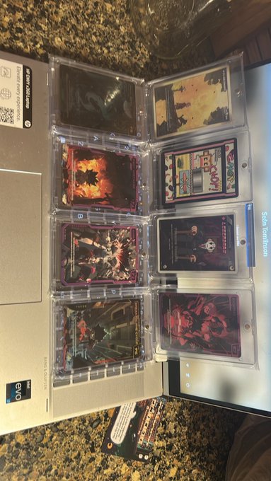 An open binder filled with trading cards in protective sleeves displayed on a granite countertop.