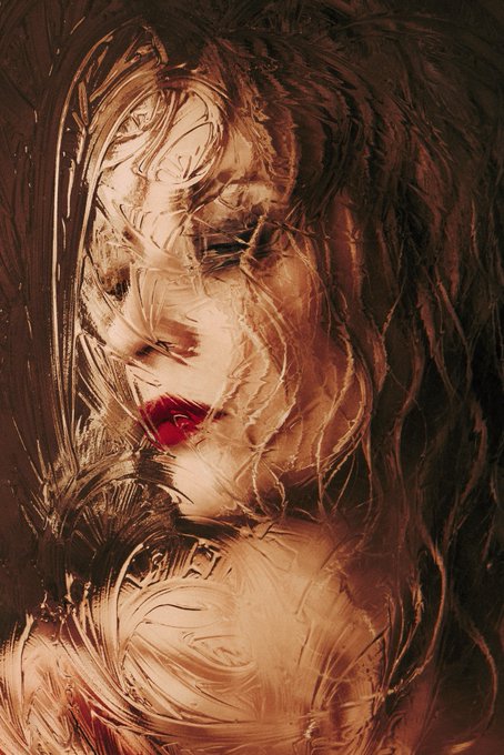 An artistic portrait of a woman with long dark hair and red lips, partially obscured by swirling, textured patterns that give it a distorted, painterly effect.