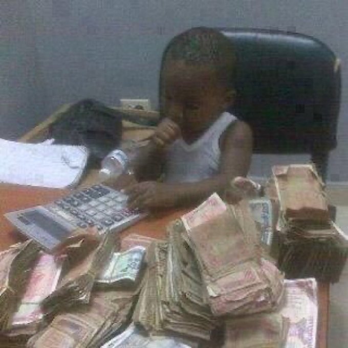 A young child sits at a desk surrounded by massive stacks of cash, casually using a calculator while appearing to count the money.

The humor ties to the caption "NFT Devs this season:" by exaggerating the sudden wealth and chaotic money-counting lifestyle the NFT developer community experienced during the crypto boom, depicting them as carefree and overwhelmed by cash despite being just kids at a desk.