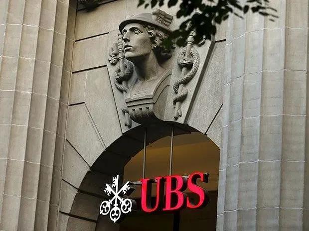 The image shows a stone archway entrance to a UBS building, featuring a classical sculpted bust above the arch and the illuminated red "UBS" logo with the company's three-keys emblem below. The scene visually represents UBS, the financial institution mentioned in the post that has significantly increased its call options position in BlackRock's Bitcoin ETF (IBIT).
