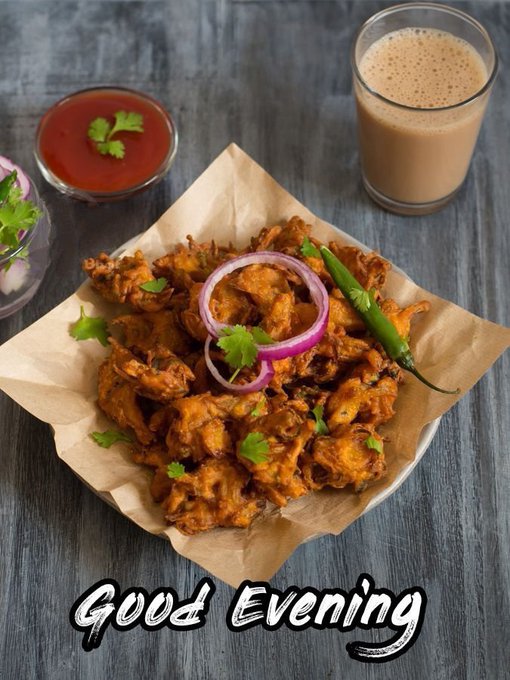 A plate of fried food garnished with red onion rings and cilantro is served with a glass of chai tea and a small bowl of red sauce, with the text 'Good Evening' overlaid at the bottom.