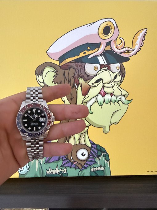 A hand holds a Rolex GMT-Master watch in front of a cartoon illustration of a green-skinned sea captain character with a large eye on his hat.