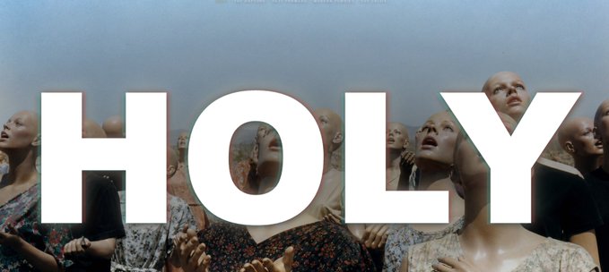 A dark, cinematic image features the large white word 'HOLY' overlaid on a crowd of bald people gazing upward.