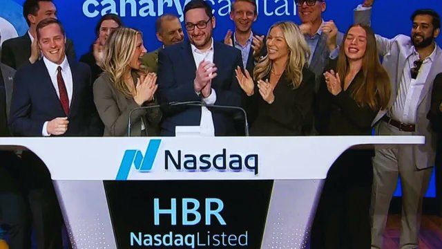 A group of people in business attire celebrate and applaud behind a Nasdaq podium displaying the ticker "HBR" and "Nasdaq Listed," marking a major milestone for Canary Capital's spot HBAR ETF on Nasdaq. The image visually captures the celebratory Nasdaq listing moment referenced in the post, highlighting the ETF's institutional credibility and Schwab accessibility amid its $3M July inflows.