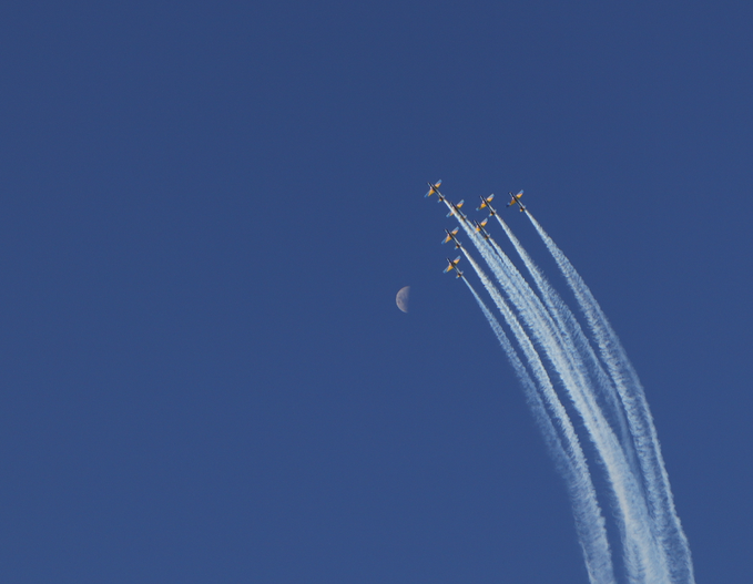 Six jets in formation fly through a clear blue sky, leaving white contrails behind them as the moon is faintly visible in the background. The image's theme of soaring through the open sky pairs with the post's motivational message about freedom and reaching new heights, fitting the spirit of the objkt NFT link promoting boundless possibility.