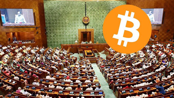 The image shows a full session of the Indian Parliament (likely the Lok Sabha) with the prominent orange Bitcoin logo superimposed on the right side, visually representing a connection between the parliamentary proceedings discussed in the caption and cryptocurrency/digital asset policy. The caption itself discusses key tax announcements from the session, including the retention of the 12.5% LTCG (Long-Term Capital Gains) tax for both retail and foreign portfolio investors, suggesting a regulatory landscape where Bitcoin and other crypto assets will continue to be taxed under this framework starting April 2026.