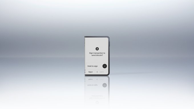 A sleek hardware wallet device displays the prompt "Sign transaction to send bitcoin?" with a "Hold to sign" button, set against a minimalist gradient background. The image visually reinforces the message of self-custody by showing a user personally approving a Bitcoin transaction on their own device, illustrating independence from third-party control.
