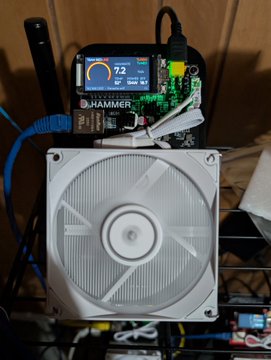 A Hammer-brand cryptocurrency mining rig displays a reading of "7.3" on its blue-lit screen, powering a white cooling fan and exposed green circuit board—likely part of the decentralized infrastructure promoted by redlinebtc.com. The setup, tagged with Parasite.space and Parasite.wtf:42069, appears to be a custom Bitcoin mining node contributing to the network.